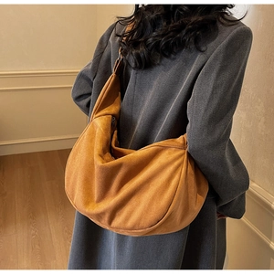 Macro view of matte suede texture and wide strap on this brown slouchy hobo tote bag