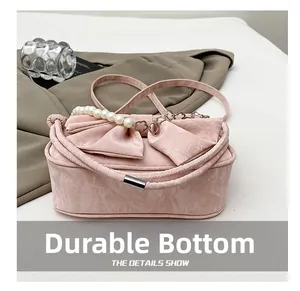 Dettaglio borsa rosa effetto marmo con fiocco grande e manico con perle decorative