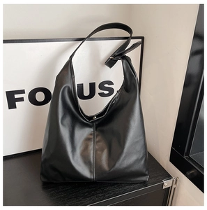 Detail of black leather tote bag showing smooth texture and adjustable shoulder strap