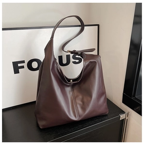 Detail of adjustable strap and matte leather texture on a large dark brown tote bag