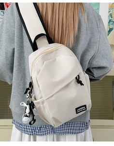 Détail du sac bandoulière blanc cassé avec zip doré et breloque baskets