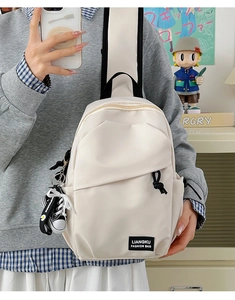 Détail du sac de poitrine en toile blanc cassé avec étiquette de mode et mini pendentif chaussure