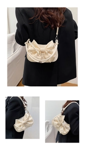 Détail d'un sac bandoulière crème avec un grand nœud décoratif et chaîne en perles