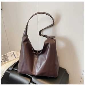 Macro detail of dark brown hobo bag showing matte leather texture and silver buckle