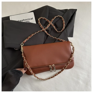Close-up of brown litchi pattern leather shoulder bag with golden chain strap on a blazer