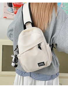 Détail d'un sac de poitrine beige avec pendentif basket et étiquette de mode tissée