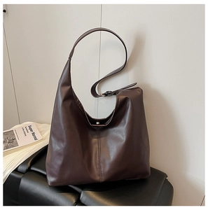 Detail of chocolate brown leather tote featuring magnetic closure and adjustable strap