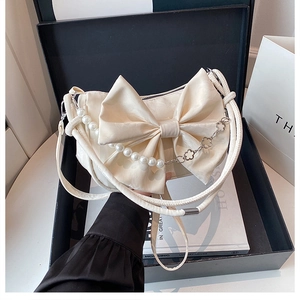 Détail du sac en satin blanc crème avec un grand nœud et une élégante anse en perles