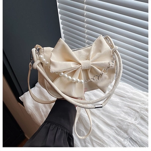 Détail du sac crème à nœud avec chaîne de perles décorative et cuir PU souple