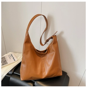 Detail view of caramel faux leather tote bag with vertical stitching on a black bench