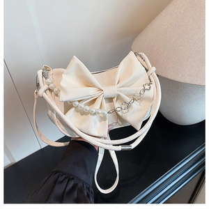 Détail du sac bandoulière crème avec grand nœud et chaîne perlée fleurie