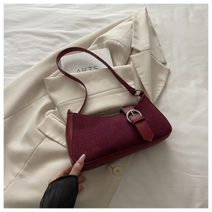 Detail of burgundy crescent bag featuring suede leather textures and silver buckle accents