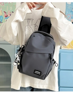 Vue détaillée du sac bandoulière gris en nylon avec logo et charms décoratifs