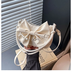 Détail du sac crème avec grand nœud et bandoulière chaîne en perles et fleurs
