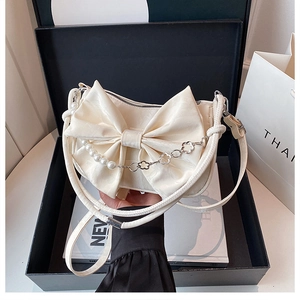 Détail du sac à bandoulière crème avec nœud et chaîne en perles dans un coffret cadeau