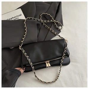 Detail of black lychee leather handbag with golden chain strap and double zipper hardware