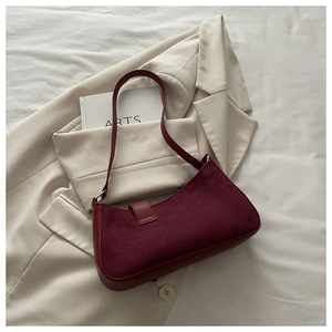 Close-up of deep red baguette bag showing suede texture and smooth leather strap detail