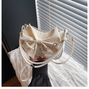 Détail du sac à bandoulière crème avec grand nœud et chaîne en perles et fleurs