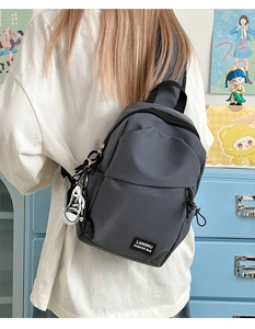 Vue détaillée du sac à bandoulière en nylon gris foncé avec étiquette et breloque basket