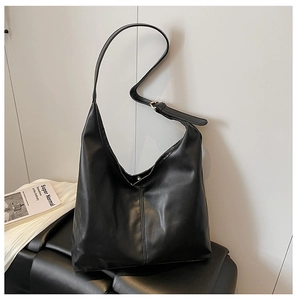 Close-up of black tote bag with vertical stitching detail and adjustable wide strap
