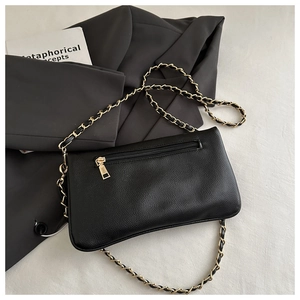 Detail of black lychee grain leather bag with a gold metal chain strap and back zipper pocket