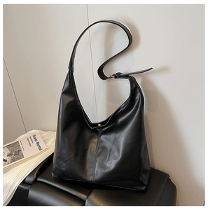 Detail of black faux leather tote bag with wide adjustable shoulder strap and metal buckle