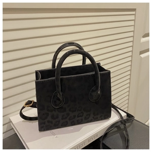 Detail of black leopard print crossbody bag with golden hardware on a decorative book