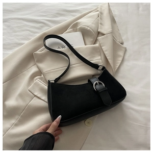 Detail of black leather crescent bag with silver buckle on a beige suit background