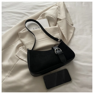 Detail of black crescent shoulder bag featuring suede texture and silver metal buckle