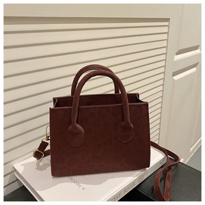 Detail view of burgundy leopard print crossbody bag with detachable strap and top handle