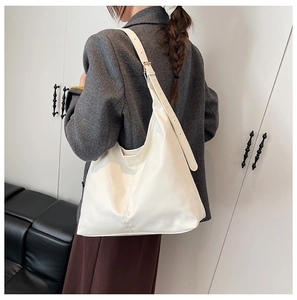 Close-up of white leather large capacity hobo bag with adjustable strap worn by model