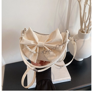 Détail du sac à nœud crème avec chaîne en perles et texture satinée élégante