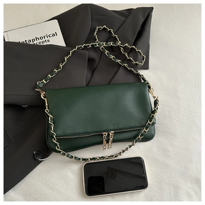 Detail of dark green lychee textured leather shoulder bag with gold chain and double zippers