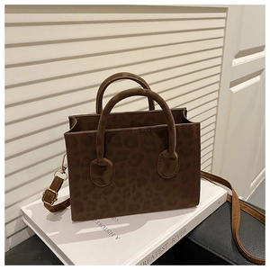 Close-up of leopard print crossbody bag with round handles and detachable shoulder strap