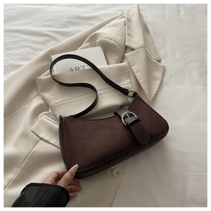 Detail of dark brown suede crescent bag with silver buckle on beige suit jacket