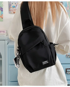 Détail du sac de poitrine noir avec sangle large et accessoire de breloque chaussure