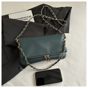 Detail view of dark green litchi grain bag with golden chain strap and smartphone for scale