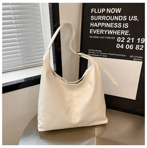 Detail of cream hobo bag with adjustable strap and golden buckle on metal table