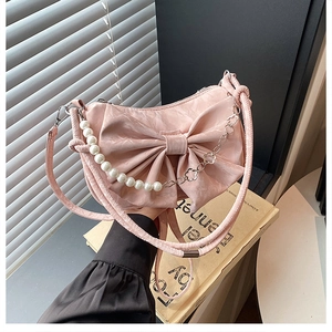 Détail du sac à main rose avec nœud, chaînes de perles et fleurs métalliques