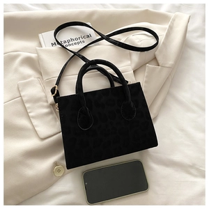 Detail of leopard print jacquard crossbody bag placed on a cream blazer with accessories