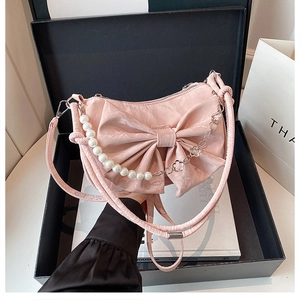 Détail du sac rose à nœud avec anse en perles et chaîne dans une boîte cadeau noire