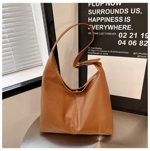 Detail of a brown matte leather shoulder bag with fine stitching and adjustable strap