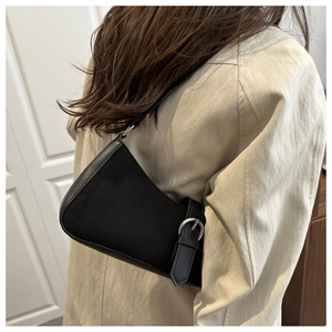 Detailed side view of minimalist black leather crescent bag with silver buckle on a model