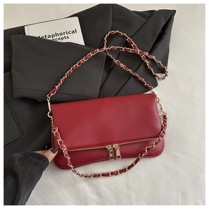 Detail of red litchi texture leather shoulder bag with gold chain strap and dual zippers