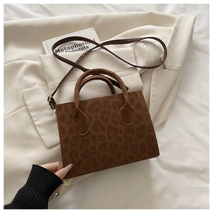 Detail view of leopard print square handbag with round handles on a blazer background