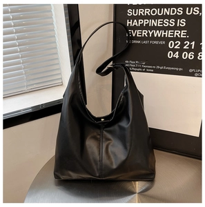 Close-up of black matte leather Hobo tote bag with vertical stitching and shoulder strap