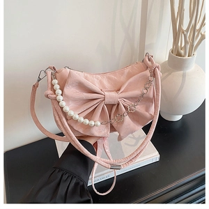 Sac à main nœud rose avec bandoulière en perles et chaîne argentée dans un décor moderne