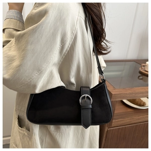 Close-up of minimalist black crescent shoulder bag with silver buckle and mixed textures