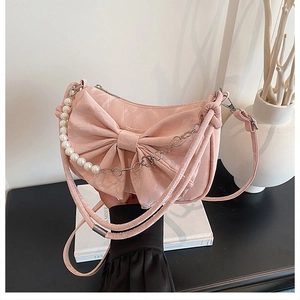 Détail d'un sac à main rose avec nœud, chaîne de perles et simili cuir à texture marbrée