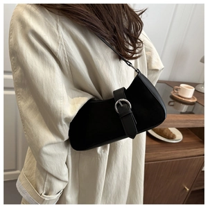 Chic black crescent underarm bag with silver buckle worn by a model in a cozy cafe